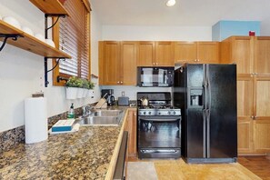 A kitchen with wooden cabinets, a black refrigerator, a stove, and a microwave. - Antlers Gulch Townhouse Next to National Forest & Golf w/shared Hot Tub, WiFi (Keystone)