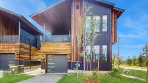 Et moderne hus med to etager, garage, store vinduer og træfacade.