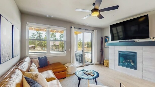 Una sala de estar con sofá, mesa de centro, chimenea, televisor y ventilador de techo.