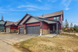 A multi-story building with a garage, a covered driveway, and a landscaped lawn. - Inviting Condo with Mountain Views, Fireplace & Space for the Entire Family (Fraser)