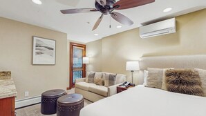 A hotel room with a bed, a ceiling fan, an air conditioning unit, a sofa, a coffee table, and a painting on the wall. - Ski-in/out studio in Lionshead w/ high-speed WiFi & shared hot tub/pools/laundry (Vail)