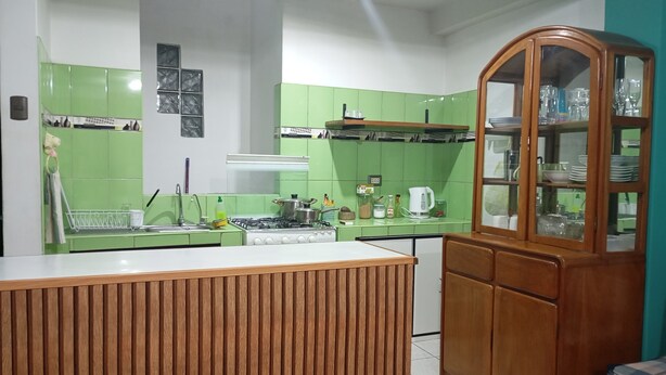 A kitchen with green cabinets, a wooden cabinet with glass doors, and a tiled floor.