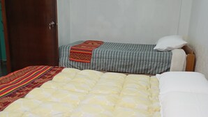A bed with a yellow quilt, a striped blanket, and a wooden headboard.
