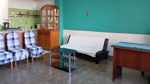 A living room with a green wall, a wooden cabinet, a sofa, and a table.