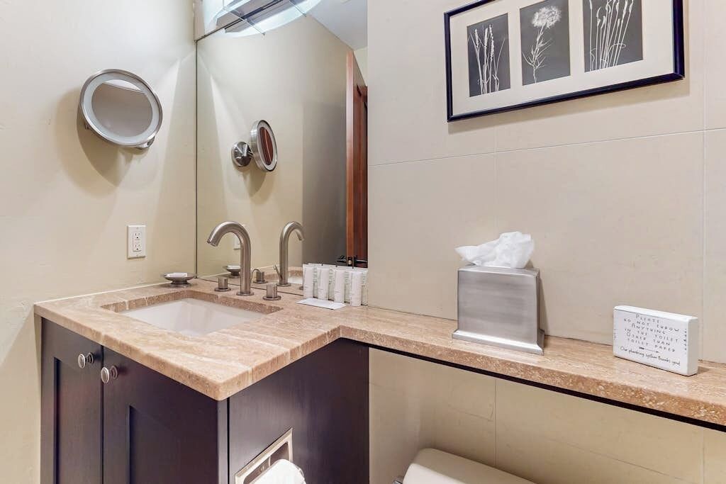 A bathroom with a double sink, a mirror, a toilet, and a framed botanical print on the wall.