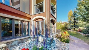 Un immeuble à plusieurs étages doté de grandes fenêtres, d’un chemin pavé en pierre et d’une grande variété de plantes.