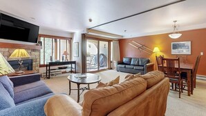 Una sala de estar con sofá, mesa de centro, televisor montado en la pared y chimenea.