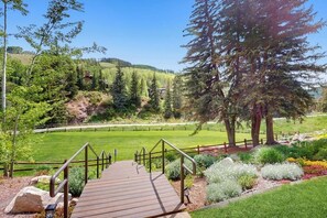 A wooden deck leading to a grassy area with a fence and trees. - Family Home in Ski-In/Ski-Out Building w/Free WiFi & shared pool, hot tubs, W/D (Vail)