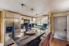 Eine Küche mit Kühlschrank, Mikrowelle und modernen Pendelleuchten.