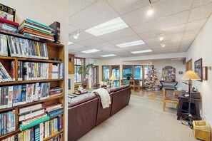 Ein geräumiges Wohnzimmer mit einer großen Bücherwand, einem Ledersofa, einem Weihnachtsbaum und einem Klavier.