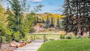 A stone pathway leading to a grassy area with trees and a view of a hilly landscape. - Ski-in/out studio w/ mountain views, fast WiFi & shared pool, hot tubs, laundry (Vail)