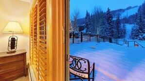 An open door leading to a snowy outdoor area with a bench and a lamp inside. - Ski-in/out studio w/ mountain views, fast WiFi & shared pool, hot tubs, laundry (Vail)
