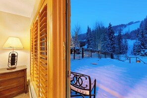 An open door leading to a snowy outdoor area with a bench and a lamp inside. - Ski-in/out studio w/ mountain views, fast WiFi & shared pool, hot tubs, laundry (Vail)