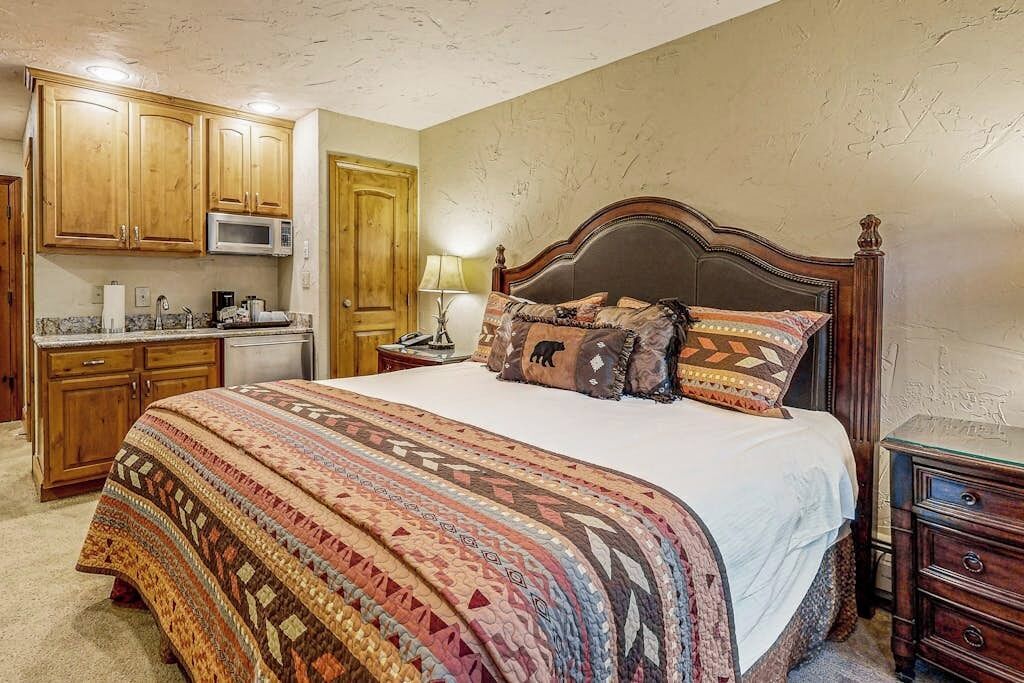 Quarto com cama grande, armários de madeira, micro-ondas e mesa de cabeceira.