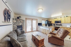 A living room with a sofa, a wooden chest, and a fireplace. - Riverfront condo with free wifi, fireplace, patio, & gas grill (Grand Lake)
