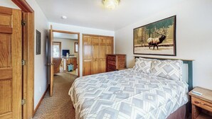 Une chambre à coucher avec un lit, une armoire en bois, un tableau représentant un élan et un bureau avec une chaise.