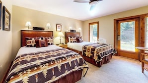 A hotel room with two beds, a ceiling fan, bedside lamps, a wooden headboard, a window with blinds, and a small wooden table. - Ski-in/out, riverfront studio w/ alpine view, fast WiFi, shared pool/hot tubs/WD (Vail)