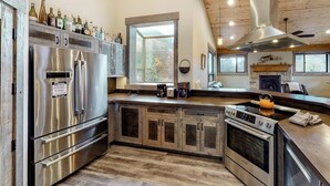 A modern kitchen with stainless steel appliances, wooden cabinets, and a large window. - Two-level home on one acre w/ mountain views and deck on Crystal River (Carbondale)