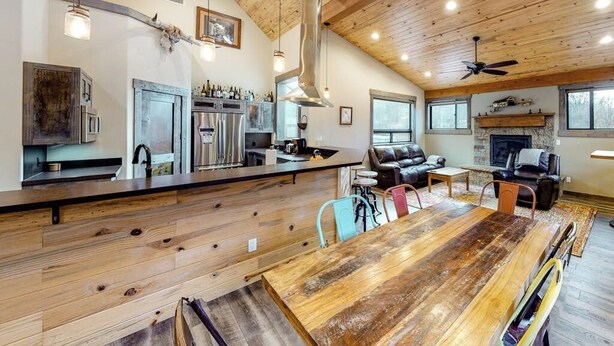 A spacious kitchen with modern appliances, a dining area with a large wooden table, and a cozy living room with leather furniture. - Two-level home on one acre w/ mountain views and deck on Crystal River (Carbondale)