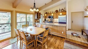 Une cuisine avec des meubles en bois, un îlot central et un coin repas comprenant une table et des chaises.