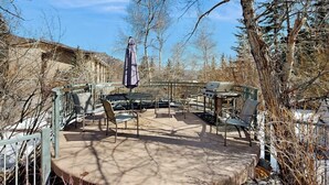 Eine Terrasse im Freien mit Grill, Stühlen und Tisch.