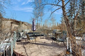 Eine Terrasse im Freien mit Grill, Stühlen und Tisch.