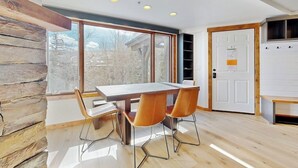 Ein modernes Interieur mit einem Holzespeisetisch, vier Stühlen, einer weißen Tür und einem großen Fenster.