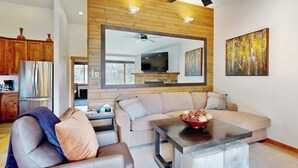 Ein modernes Wohnzimmer mit einer Couch, einem Couchtisch, einem Fernseher und Holzvertäfelung an der Decke.