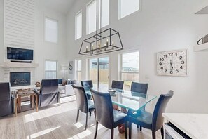 Ein geräumiges Wohnzimmer mit einem Glastisch, Ledersesseln, einem Kamin und einem großen Fenster.
