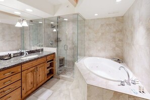 A modern bathroom with a glass-enclosed shower, a freestanding bathtub, and wooden cabinetry.