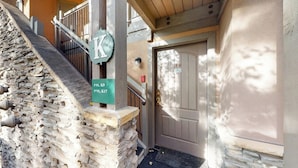 A stone staircase leading to a wooden door with a mailbox and a green sign indicating room numbers.