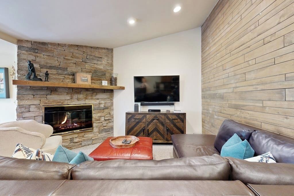 A living room with a fireplace, leather sofa, and a television on a wooden cabinet.
