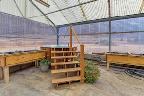 Ein Gewächshaus mit einer Holzspirale, einem Tisch und Topfpflanzen.