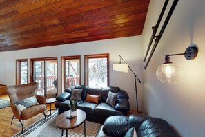 Ein Wohnzimmer mit Holzboden, einem Ledersofa, einem braunen Sessel, einem Couchtisch und einer Stehlampe.