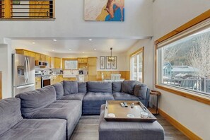 Ein modernes Wohnzimmer mit einer Eckcouch, einem Couchtisch und Blick auf eine verschneite Landschaft durch große Fenster.