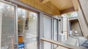 Un interior moderno con puertas de cristal correderas, una terraza de madera y mobiliario exterior.