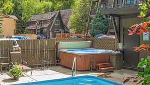 Una piscina con hidromasaje, terraza de madera y patio trasero cercado.
