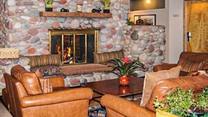 Una chimenea de piedra, sofás de cuero y una mesa de centro en un salón acogedor.