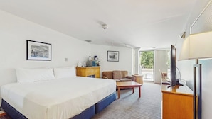 Habitación de hotel con una cama grande, un escritorio, una silla y un televisor.