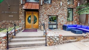 A stone building with a double door entrance, steps leading up to it, and a blue outdoor seating area.