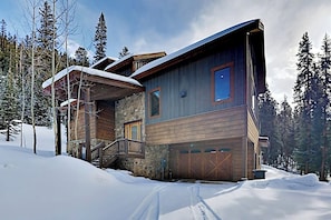 Eine mehrstöckige Blockhütte mit Steinunterbau, einer Holzdiele und einer Garage.