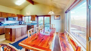 Un'ampia cucina con mobili in legno, una grande isola e un'area pranzo con tavolo e sedie in legno.