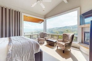 Ein Schlafzimmer mit einem großen Bett, zwei Sesseln mit ZEBRA-Muster, einem Kamin und einem Balkon mit schöner Aussicht.