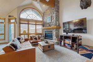 Ein gemütliches Wohnzimmer mit Kamin aus Stein, einem großen Fernseher und einer bequemen Sitzecke.