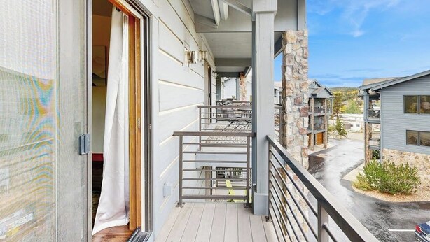 Un balcone con vista sugli edifici circostanti, un pilastro in pietra e cielo sereno.