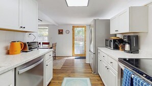A compact kitchen with white cabinets, a microwave, a toaster, and a kettle.