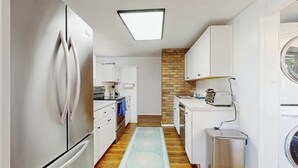 A compact kitchen with a refrigerator, a washing machine, and a microwave.