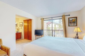 A hotel room with a bed, a television, a balcony with a view, and a door leading to a bathroom. - Stunning 1st-floor ski-in condo with hot tubs, fireplace, & gym (Breckenridge)