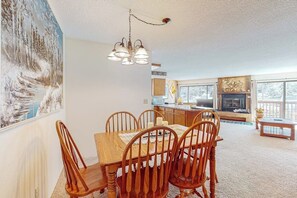 A dining area with a wooden table and chairs, a chandelier, and a painting on the wall. - Stunning 1st-floor ski-in condo with hot tubs, fireplace, & gym (Breckenridge)