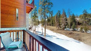 Eine Holzhütte mit einem Balkon mit Blick auf eine verschneite Landschaft und Bäume.